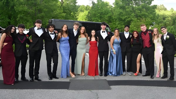 Eine Gruppe formell gekleideter Personen posiert vor bewaldetem Hintergrund auf dem Gelände der Wilson's Hospital School.