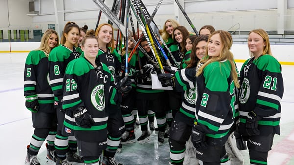 Eine Gruppe weiblicher Hockeyspielerinnen der Winchendon School auf der Eisbahn im Teamoutfit.