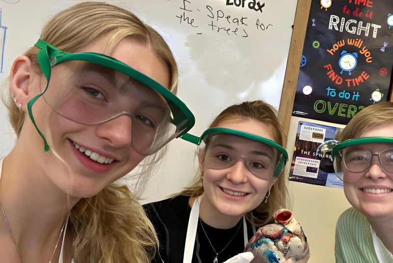 Drei Schüler der Winchendon School in Schutzbrillen stehen im Klassenraum vor einem Whiteboard.