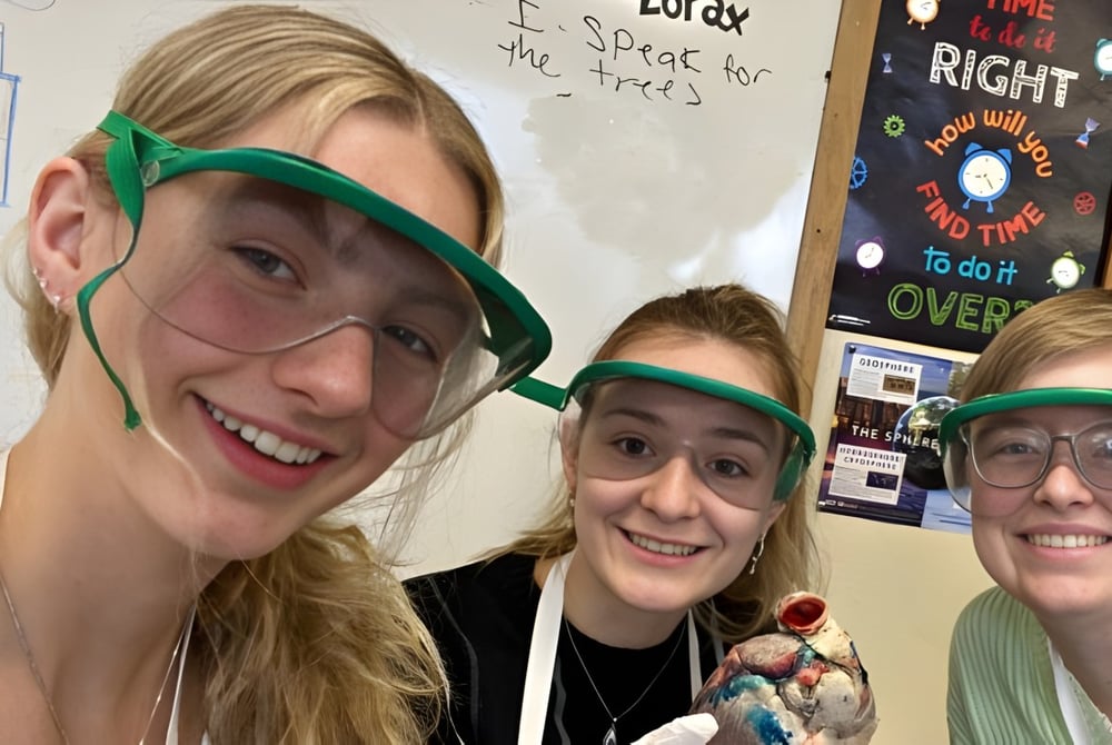 Drei Schüler der Winchendon School in Schutzbrillen stehen im Klassenraum vor einem Whiteboard.