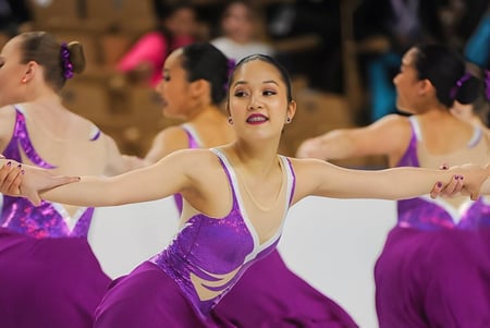 Eine Gruppe Tänzerinnen der Winchendon School New York City führt in violetten Kostümen auf einer Bühne eine Tanzaufführung auf.