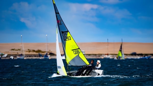 Ein Segelboot mit gelbem Segel fährt auf dem Wasser nahe dem Campus von Winchester College.