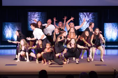 Schüler der Windermere Preparatory School führen eine dynamische Tanzperformance auf der Bühne mit farbiger Beleuchtung auf.