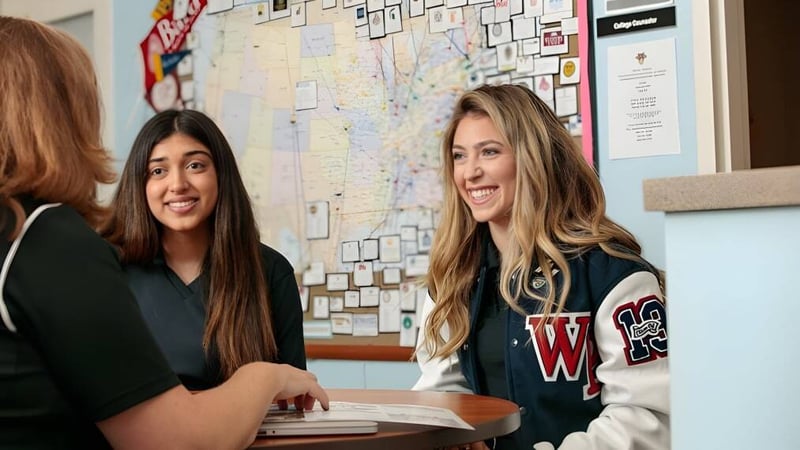 Zwei Schülerinnen sitzen an einem Tisch im Klassenraum der Windermere Preparatory School mit einem Pinnwand-Hintergrund.