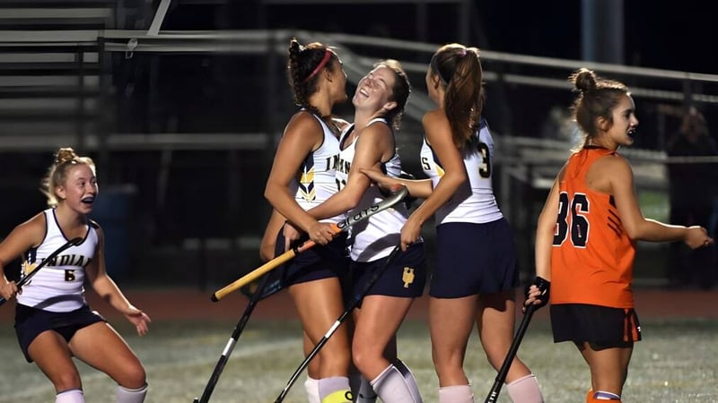 Eine Gruppe weiblicher Sportlerinnen versammelt sich in Sportkleidung auf dem Sportplatz der Windermere School bei Nacht unter Flutlicht.