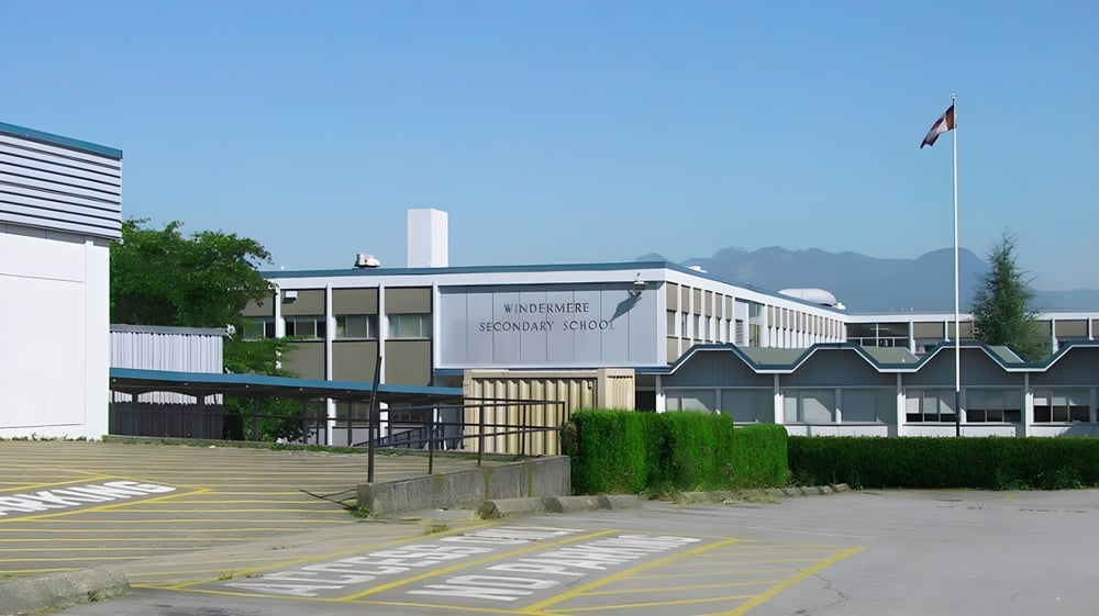 Das moderne mehrstöckige Gebäude der Windermere Secondary School mit einer wehenden Schweizer Flagge im Vordergrund.