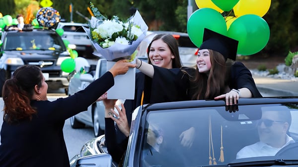 Schülerinnen der Windsor Secondary School in Abschlusskappen und -mänteln halten Blumen auf der Abschlussfeier.