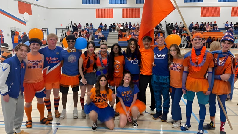Eine große Gruppe Schüler der Winston Churchill High School steht in ihren orange-blauen Uniformen in einer Sporthalle.