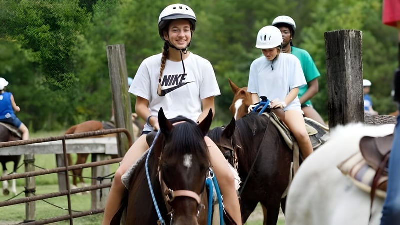 Zwei Personen reiten mit Helmen auf Pferden in einem umzäunten Außenbereich auf dem Campus der Winston Salem Christian School.