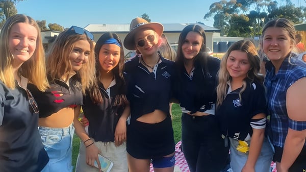 Eine Gruppe Schülerinnen steht draußen auf dem Gelände der Wirreanda Secondary School vor einem Gebäude und Bäumen.