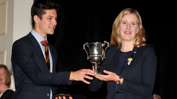 Zwei Personen halten bei einer offiziellen Veranstaltung der Wisbech Grammar School gemeinsam einen Pokal.
