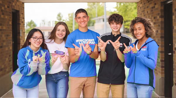Eine Gruppe von fünf Schülerinnen und Schülern steht vor einem Backsteingebäude auf dem Campus der Wisconsin Lutheran High School.