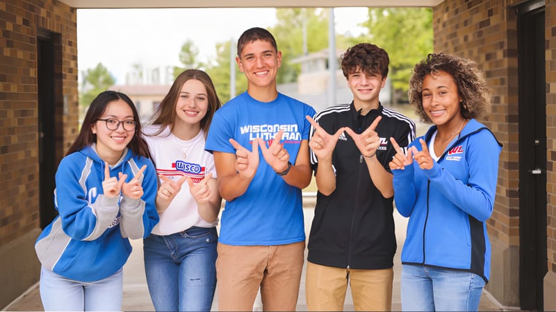 Eine Gruppe von fünf Schülerinnen und Schülern steht vor einem Backsteingebäude auf dem Campus der Wisconsin Lutheran High School.