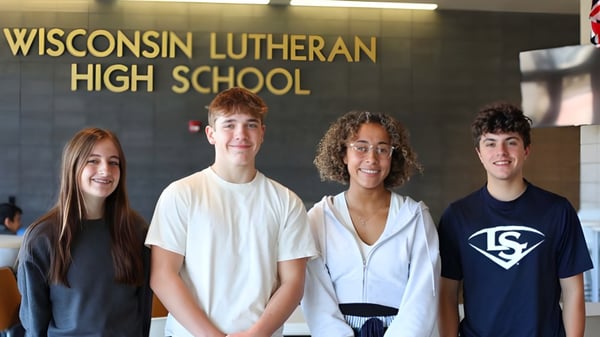 Vier Schülerinnen und Schüler stehen vor dem Schild der Wisconsin Lutheran High School.
