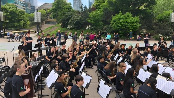 Musizierende Schülerinnen und Schüler der W.J. Mouat Secondary School treten im Freien in einem Park auf.