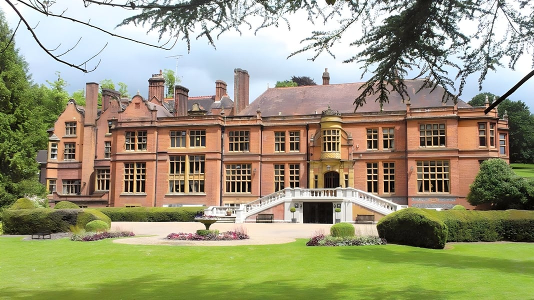 Das historische Hauptgebäude der Woldingham School steht umgeben von einem gepflegten Garten mit grünem Rasen.