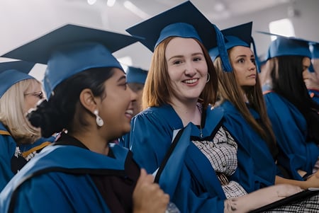 Eine Gruppe von Absolventen in blauen Talaren steht im Flur der Wollongong University.