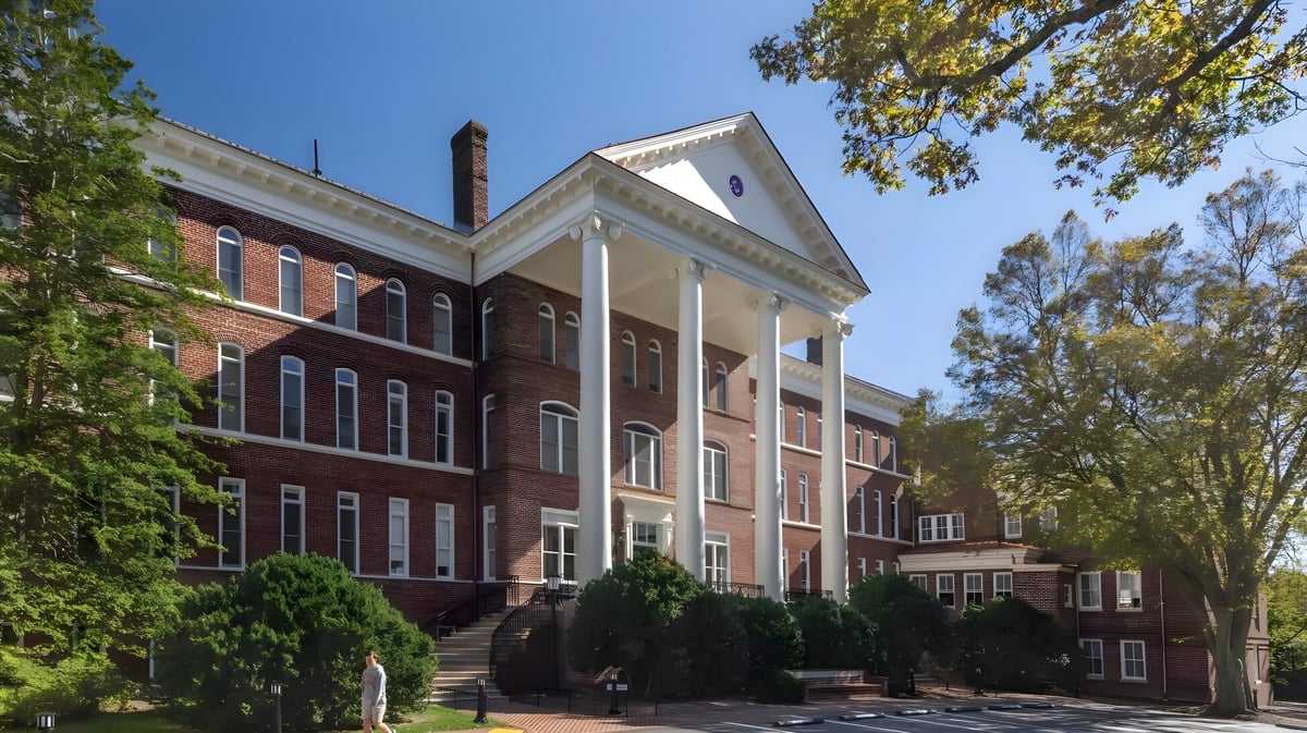 Das Backsteingebäude mit weißen Säulen der Woodberry Forest School ist von üppigem Grün umgeben.