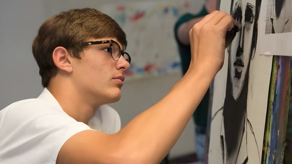 Ein Junge mit Brille steht vor einer Wand mit bunten Kunstwerken auf dem Campus der Woodberry Forest School.
