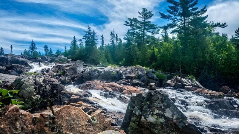 Eine felsige Landschaft mit einem Wasserfall und immergrünen Bäumen auf dem Gelände des Woodbridge College.