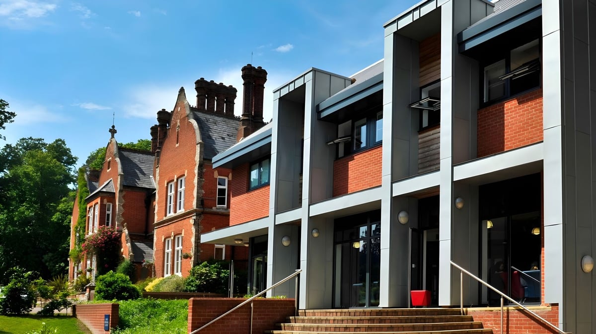 Das moderne Backsteingebäude der Woodbridge School ist von grünen Bäumen umgeben und steht unter einem klaren blauen Himmel.