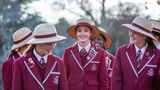 Eine Gruppe von Schülerinnen und Schülern der Woodford House steht in einem parkähnlichen Bereich mit Bäumen und Grünflächen.