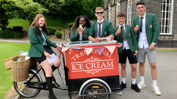 Schüler der Woodhouse Grove School stehen um einen Eiswagen auf einer Wiese vor einem Backsteingebäude.