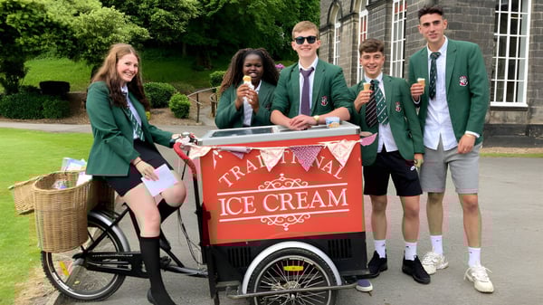 Schüler der Woodhouse Grove School stehen um einen Eiswagen auf einer Wiese vor einem Backsteingebäude.