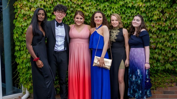 Sechs Personen in formeller Kleidung posieren vor einer efeubewachsenen Wand auf dem Gelände der Woodhouse Grove School.