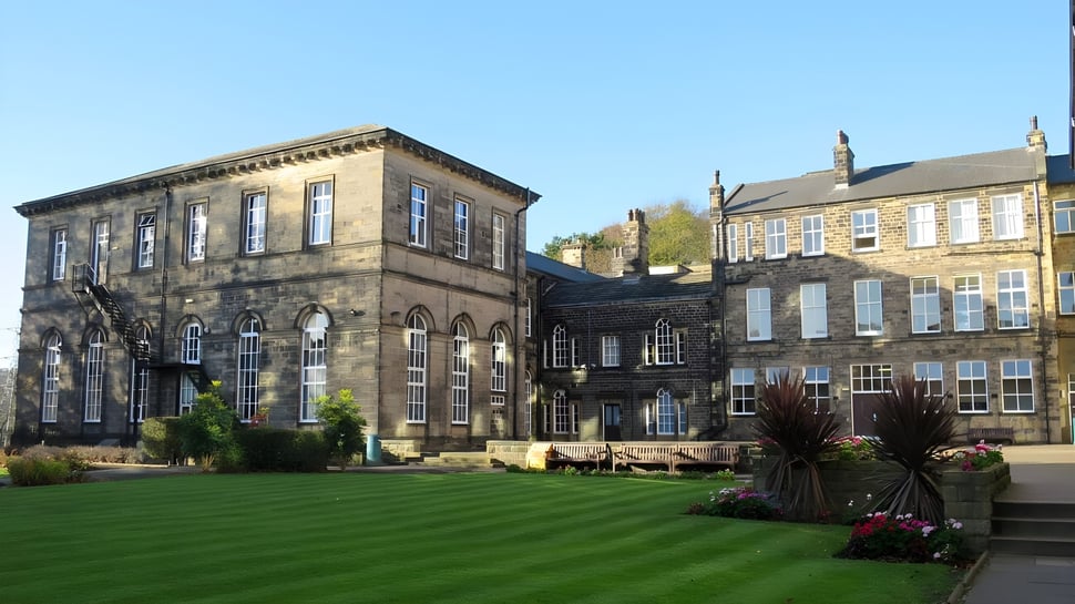 Das historische Hauptgebäude der Woodhouse Grove School ist von gepflegtem Rasen und Blumenbeeten umgeben.