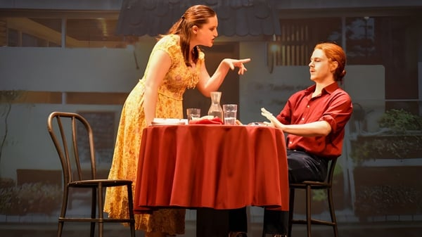 Zwei Personen unterhalten sich an einem Tisch mit rotem Tischtuch auf dem Campus der Woodlands Academy of the Sacred Heart.