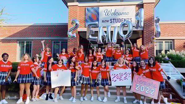 Schülerinnen und Schüler der Woodlands Academy of the Sacred Heart begrüßen die neuen Schülerinnen und Schüler des Jahrgangs 2022 vor einem Backsteingebäude.
