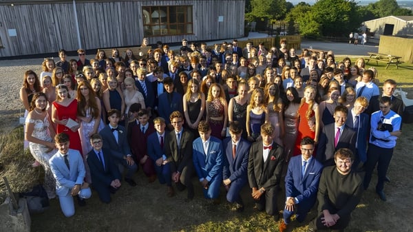 Eine Gruppe von Schülerinnen und Schülern steht vor einem Holzgebäude auf dem Außengelände der Woodroffe High School.