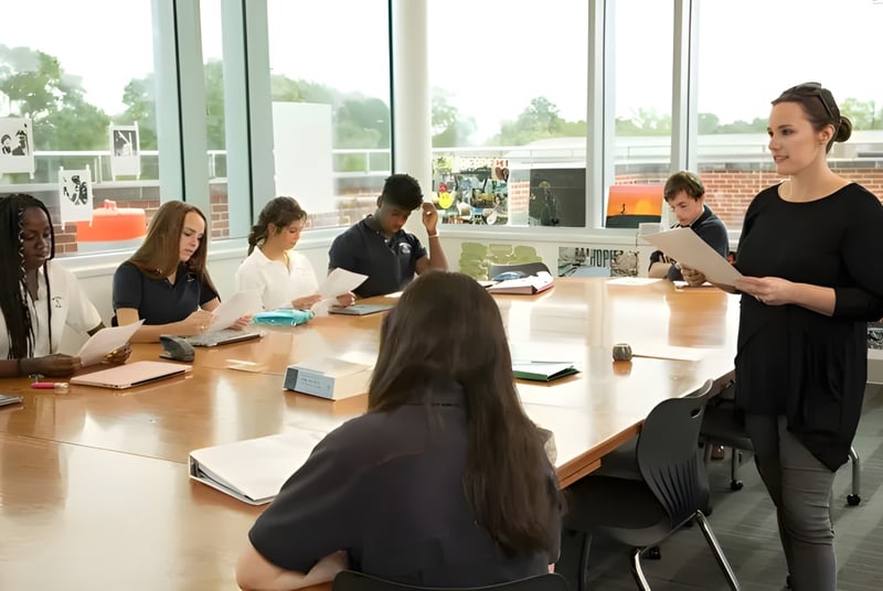 Schüler der Woodward Academy arbeiten gemeinsam an einem Tisch in einem Klassenraum mit großen Fenstern.