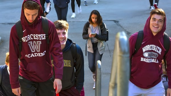 Schüler der Worcester Academy gehen auf einer belebten Straße in der Stadt.