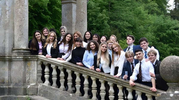 Eine Gruppe von Schülerinnen und Schülern steht auf dem Balkon des Worksop College umgeben von grüner Vegetation und steinernen Säulen.