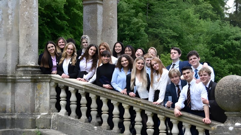 Eine Gruppe von Schülerinnen und Schülern steht auf dem Balkon des Worksop College umgeben von grüner Vegetation und steinernen Säulen.