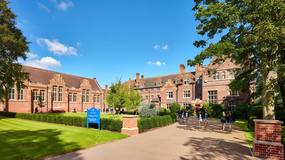Der Campus von Worksop College zeigt einen gepflasterten Weg durch eine grüne Wiese umgeben von Backsteingebäuden unter blauem Himmel.