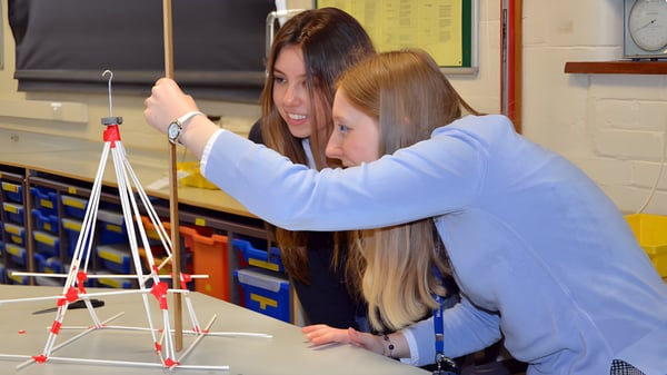 Zwei Schülerinnen der Worth School arbeiten gemeinsam an einer bunten Struktur aus Stäben und Verbindern im Klassenraum.
