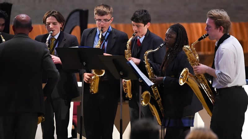 Eine Gruppe von Schülern der Worth School spielt auf der Bühne verschiedene Musikinstrumente.