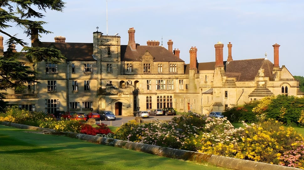 Das historische Schlossgebäude der Worth School ist umgeben von gepflegten Gärten und einer grünen Rasenfläche.