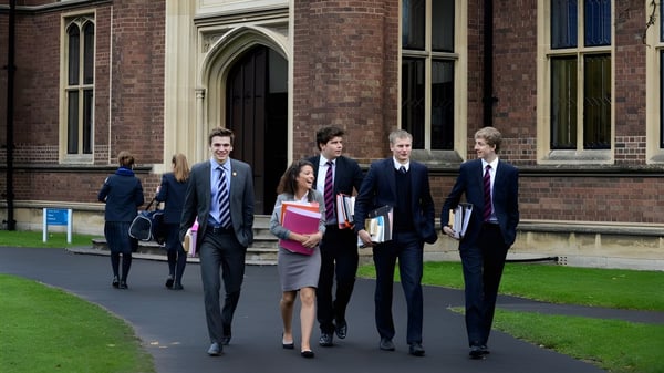 Eine Gruppe gut gekleideter Schülerinnen und Schüler geht auf dem Campus des Wrekin College an einem Backsteingebäude und einer Rasenfläche vorbei.