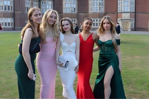 Eine Gruppe junger Frauen in formeller Kleidung posiert vor dem historischen Backsteingebäude des Wrekin College.