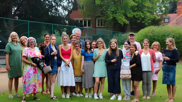 Eine Gruppe von Schülerinnen steht im Freien auf dem Campus der Wychwood School vor Bäumen und Gebäuden.