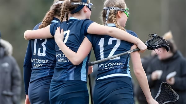 Zwei Sportlerinnen der Wycombe Abbey School stehen auf dem Sportfeld und umarmen sich.