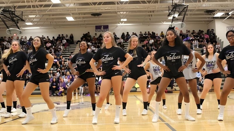 Eine Gruppe Schülerinnen in schwarzen Uniformen steht auf dem Basketballfeld in der Sporthalle der Wyoming High School.
