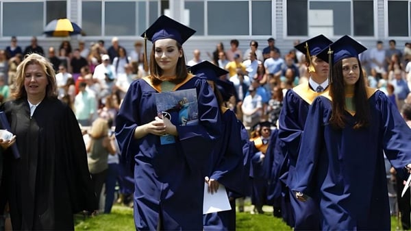 Eine Gruppe Absolventen in blauen Talaren steht vor einem Gebäude auf dem Campus der Wyoming Seminary College Preparatory.