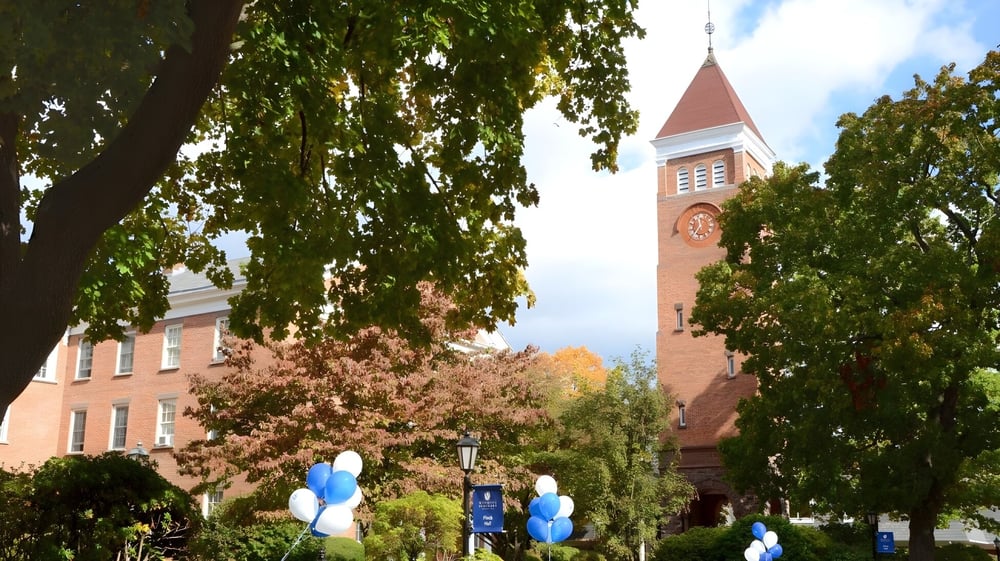 Das Backsteingebäude mit steilem Turm auf dem Campus der Wyoming Seminary College Preparatory ist von grünen Bäumen umgeben.