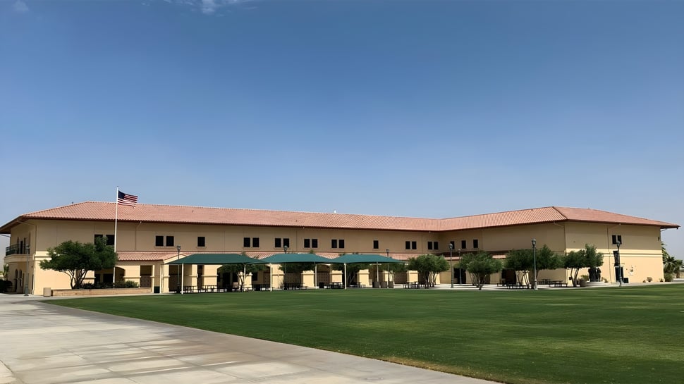 Das zweistöckige Hauptgebäude von Xavier College Preparatory High School steht vor einem klaren blauen Himmel mit gepflegtem Rasen und Palmen.