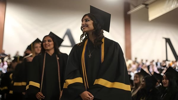 Absolventen der Xavier College Preparatory High School tragen schwarze Talare und stehen in einem Flur mit Menschen im Hintergrund.